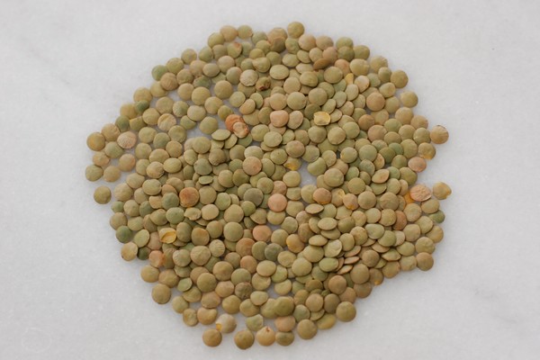 Unsorted lentils spread over a cutting board