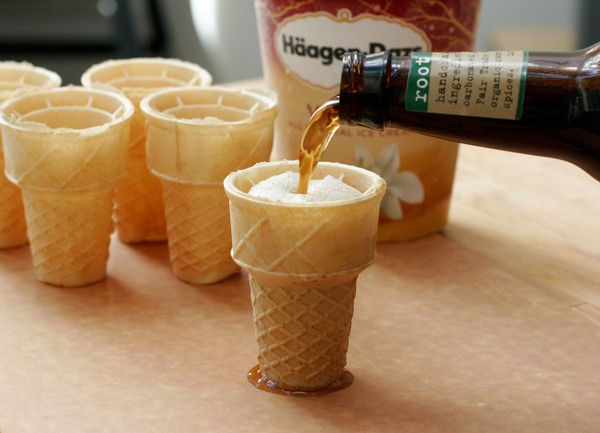 Filling the ice cream cones Pouring a bottle of root beer into a flat-bottomed ice cream cone