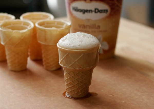 Root beer foaming over the rim of a flat-bottomed ice cream cone