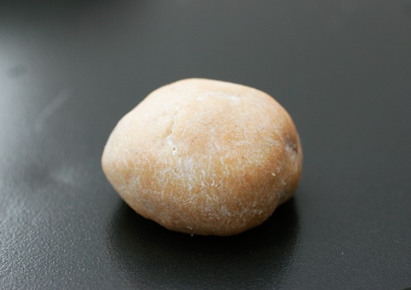 A single, brown, potato-shaped, baked cookie on a baking sheet
