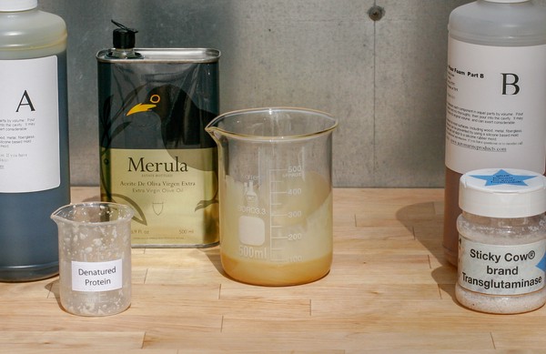 Beaker of expanding foam beginning to expand; other bottles/beakers nearby